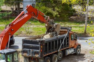 Truck with excavator loading for removal of waste building demolition debris construction