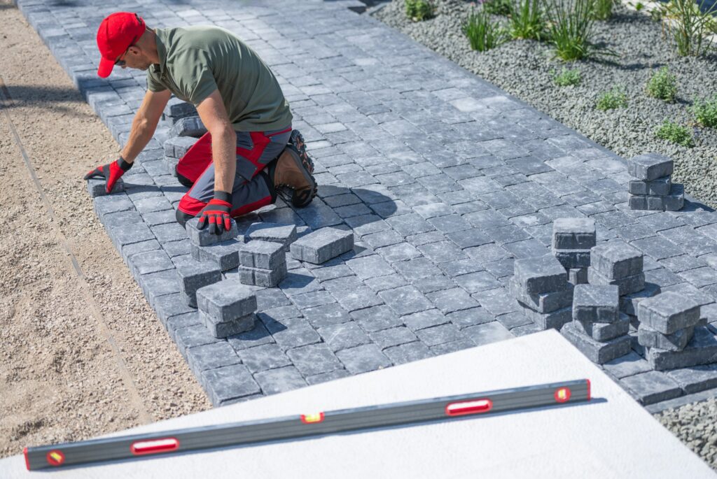 Person Laying Pavers for a Walkway in a Residential Garden on a Sunny Day